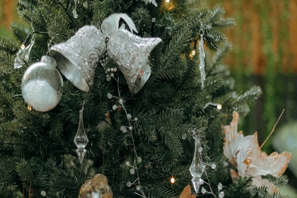 Cozy living room adorned with glowing Christmas tree, garlands, and red-gold ornaments
