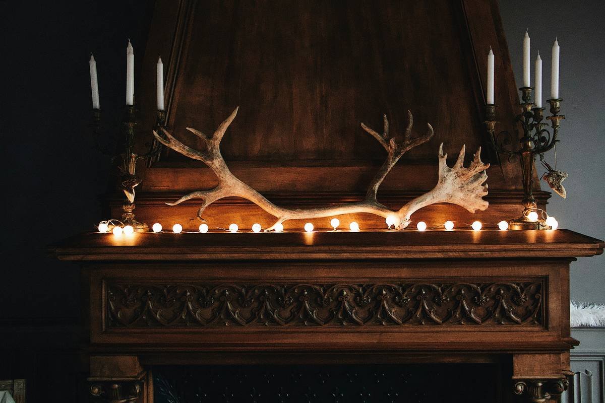 Before: generic red plastic Christmas decor on mantel. After: rustic pinecone garland with eucalyptus, white-painted cones, and brass candles