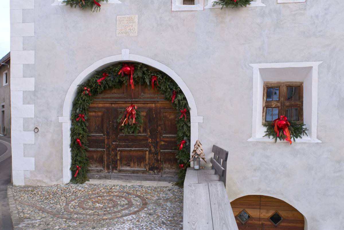 A festive cheap door hanger made of burlap and pine cones hanging on a wooden front door