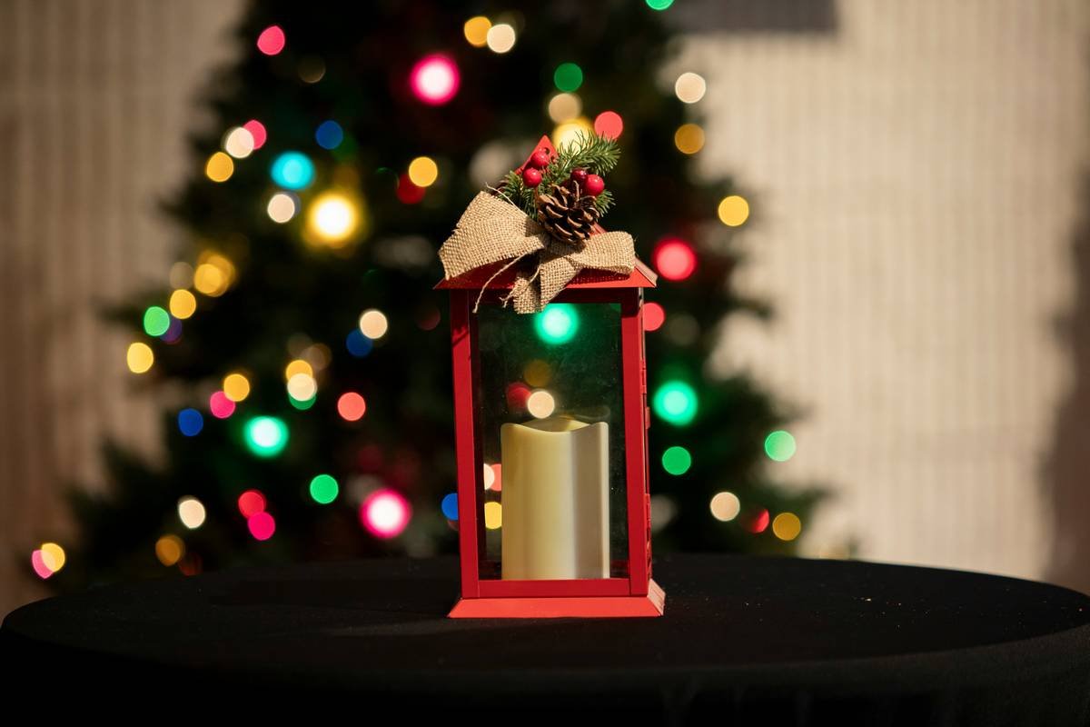 Weatherproof outdoor lantern timer installed on a front porch post with festive greenery, showing digital display and power cord