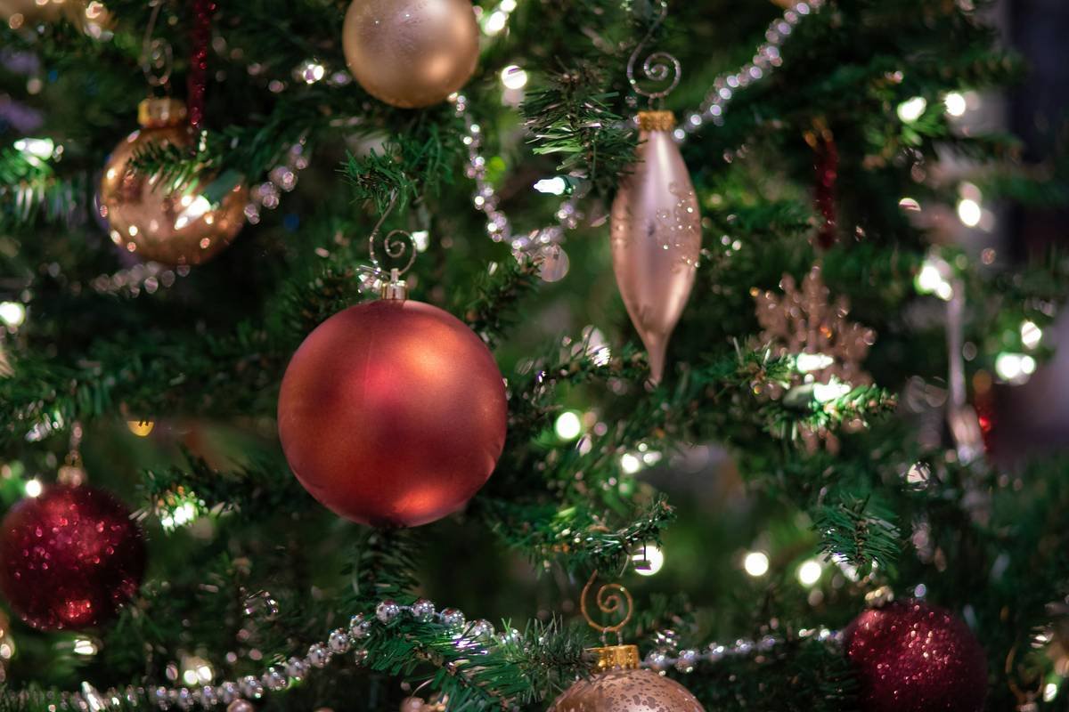 A Christmas tree adorned with an ombre ball set transitioning from emerald green to gold