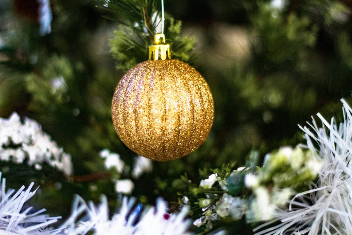 Close-up of delicate gold leaf glass Christmas ornament hanging on a fir tree branch