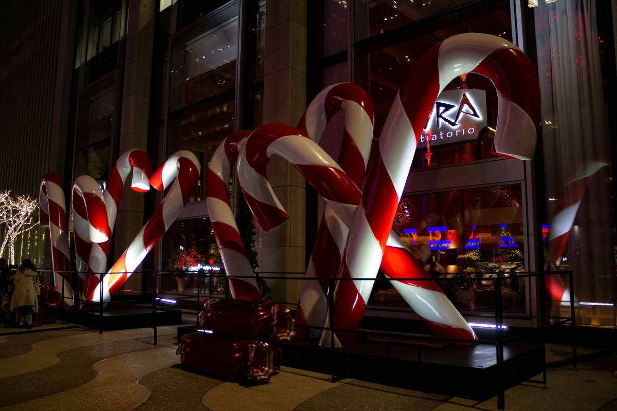 giant candy decoration mounted securely on a front porch with LED string lights illuminating red and white swirls