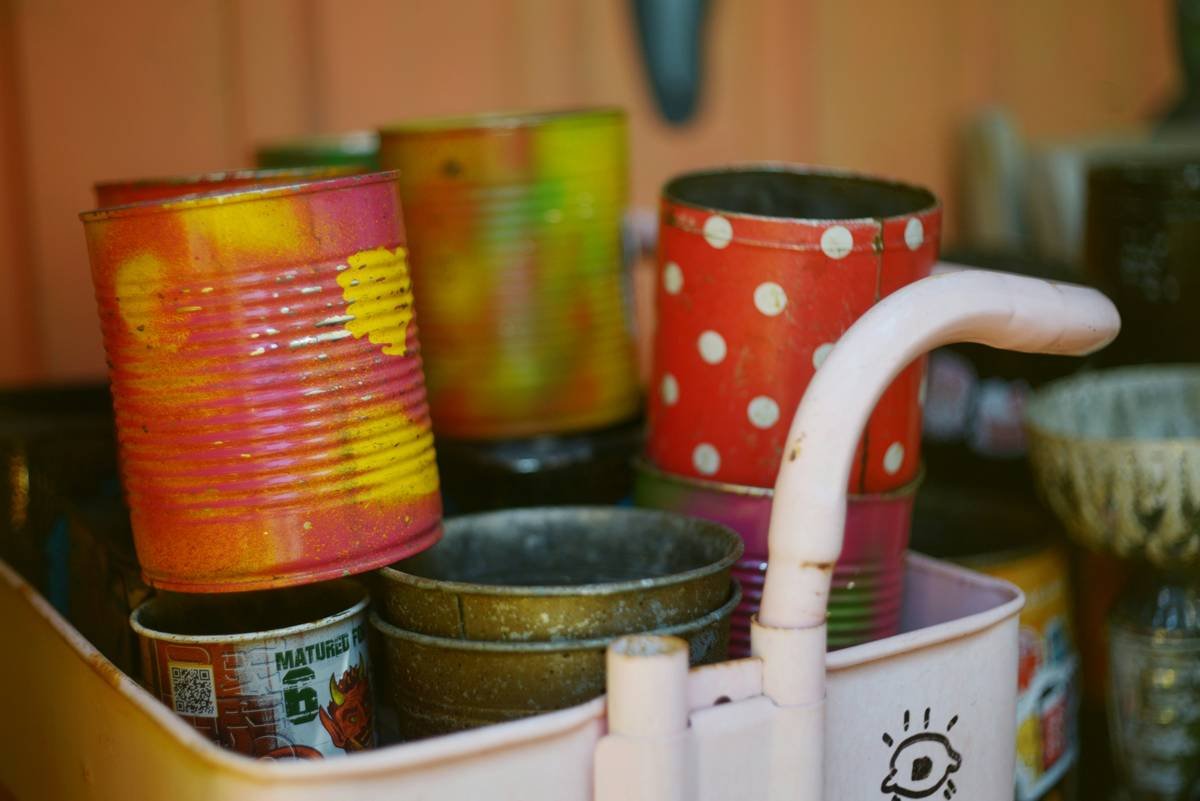 tin can lantern craft showing three upright, hammered soup cans with candlelight glowing through punched star and dot patterns